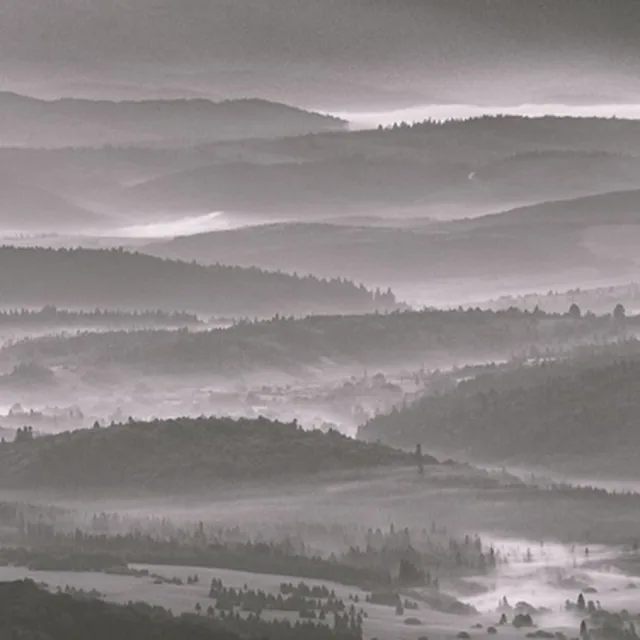 Mist lying in the folds of a range of hills, layer behind layer.